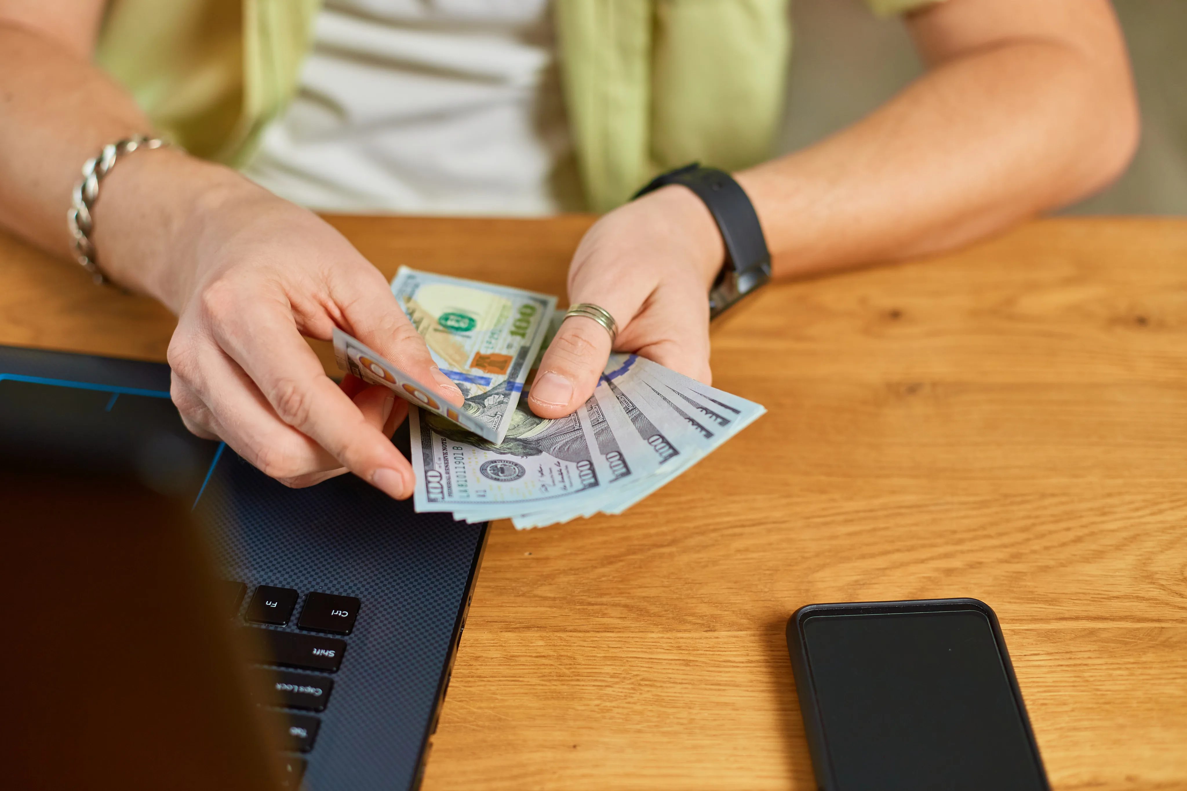 Hands counting currency near a laptop — campaign spending control