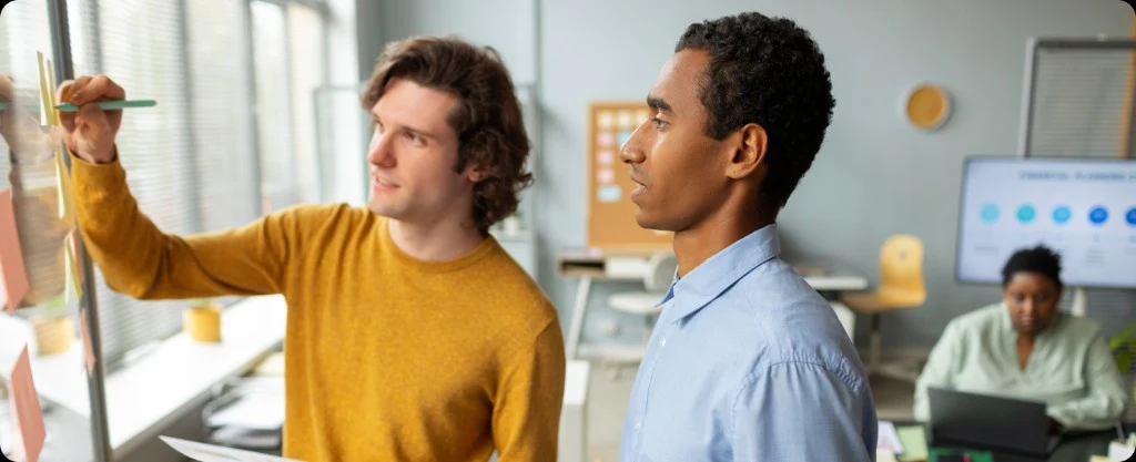 Team collaborating at a glass board with sticky notes in a modern office